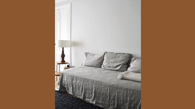 Dans la chambre d’ami, lit de jour recouvert de lin lavé et froissé et lampe avec pied en bois tourné chinée en brocante.