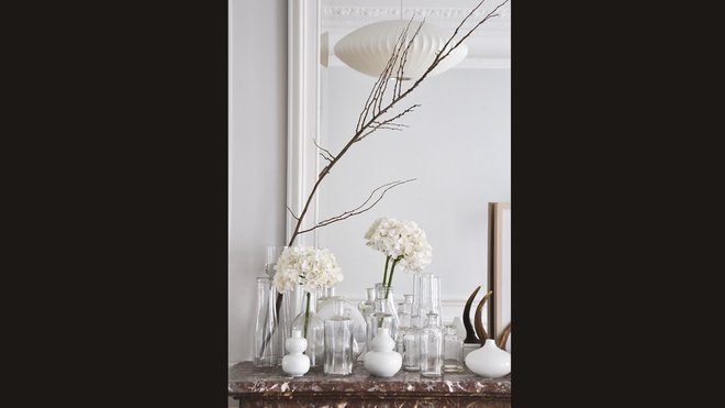 Sur une cheminée, petite accumulation de vases en verre et céramique pour animer l’espace sans le charger.