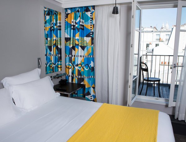 La sobriété de la chambre met en valeur la vue sur les monuments parisiens.