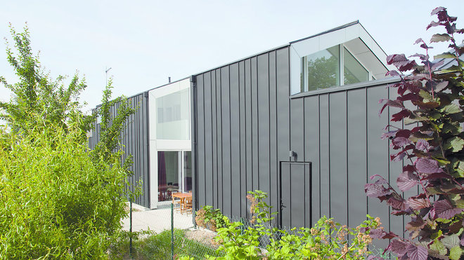 Cette maison longère située à Carquefou près de Nantes a été construite dans une zone rurale. Certifiée BBC, elle revisite le style des longères ardoisées et des hangars tôlés environnants. Sur un terrain très étroit, l'habitation se développe autour d'un plan rectangulaire séquencé exploitant au maximum la parcelle. Elle est ponctuée par des espaces en creux dédiés aux terrasses. Réalisation 5W.