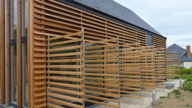 Hommage contemporain à l'architecture traditionnelle des granges, cette construction passive en Douglas non traité affiche une volumétrie épurée avec une partie habitation compacte. Au Sud, un bardage bois horizontal dissimule des portes rabattables. Réalisation Atelier RVL associé à Golven Le Pottier.