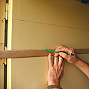 Etape 1 : Sur la porte préalablement repeinte en deux couches de peinture glycérophtalique d’aspect satiné, couleur ocre jaune, réaliser le traçage des deux traverses (haute et basse) de la porte ; la largeur sera de plus ou moins 22 cm. Utiliser un crayon à papier sec type H pour le traçage.