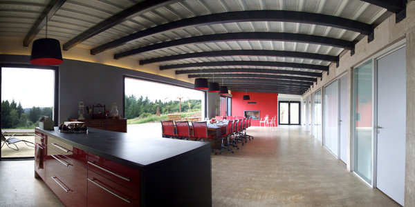 Le corps central de la maison est composé d’un espace entièrement décloisonné. Seul le mobilier distingue la cuisine de la salle à manger et du salon. Les espaces privés des trois générations d’occupants s’organisent autour de ce grand espace de vie mi-intérieur, mi-extérieur, avec escalier double.