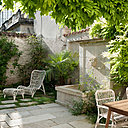 Le jardin de ville largement ombragé possède une fontaine. Fauteuils avec repose-pieds, modèle Lucy Lounge, en résine polyéthylène, Vincent Sheppard.