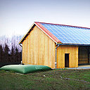 Une Citerne Verte raccordée à la descente de gouttière d’un hangar.