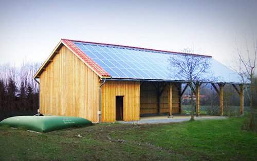 Une Citerne Verte raccordée à la descente de gouttière d’un hangar.