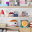 Les accessoires sont exposés sur des étagères en bois et métal. On y  trouve coussins, doudous, lampes pour la chambre des petits.