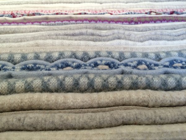 Long tapis qui répond au nom de Pépita, est un assemblage de pulls coupés en lanières, pressées et cousues en double épaisseur pour réaliser un tapis moelleux, les bordures rappellent le point  Pépita utilisé en vannerie.