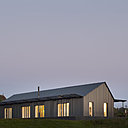 L’enveloppe de la façade est revêtue d’un bardage métallique ondulé gris foncé, évoquant la couleur des séchoirs à tabac locaux.