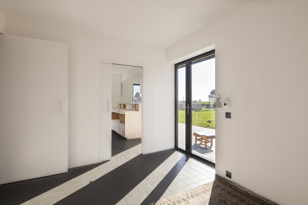 Aux précieuses harmonies de l’extérieur s’oppose la clarté intérieure. Les espaces à vivre de la maison sont tournés vers le jardin, via les vastes baies vitrées cadrant le paysage. Les vantaux dissymétriques ajoutent une note de sophistication.