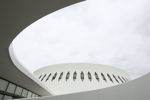 L’affinement vers le haut du volcan amplifie l’élan dynamique de cette architecture inédite. Niemeyer a rabaissé la place pour créer une construction qui tienne compte du climat (les vents de la mer) et de l’environnement (l’harmonie des bâtiments alentour). La place multiplie les dimensions architecturales : les passants ne voient pas les éléments d’un seul point de vue, ils peuvent aussi regarder la place d’en haut. Est dissimulé ce qui peut l’être, et la surface du sol est aussi aérée que possible.