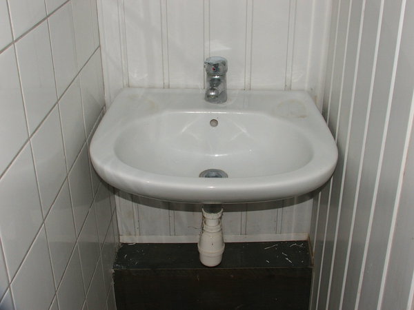 Trônant au centre du lavabo, l’ancien mitigeur de salle de bains usé et terni par le temps.