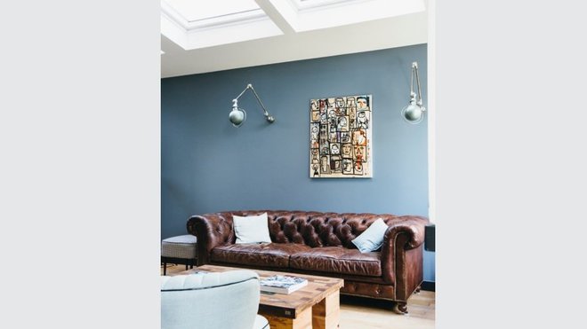 Dans l’extension, le salon est mis en valeur par un pan de mur bleu ciel. Canapé de style Chesterfield, Flamand, et luminaires en appliques, Jieldé. Dans l’extension, le salon est mis en valeur par un pan de mur bleu ciel. Canapé de style Chesterfield, Flamand, et luminaires en appliques, Jieldé.