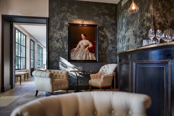 Autour du bar, en toile de fond, le papier-peint crée un espace plus intime, sous l’œil attentif d’un portrait de famille.