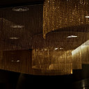 Décor organique avec ce système de rideaux statiques formant des cylindres pour animer un plafond et jouer avec la lumière des spots. Chaîne en aluminium anodisé haute résistance des couleurs à l’extérieur. Réalisable en deux espacements de chaîne, 15 couleurs brillantes et 13 teintes mates. Création Kriskadécor.