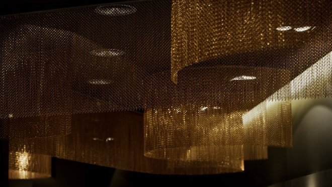 Décor organique avec ce système de rideaux statiques formant des cylindres pour animer un plafond et jouer avec la lumière des spots. Chaîne en aluminium anodisé haute résistance des couleurs à l’extérieur. Réalisable en deux espacements de chaîne, 15 couleurs brillantes et 13 teintes mates. Création Kriskadécor.