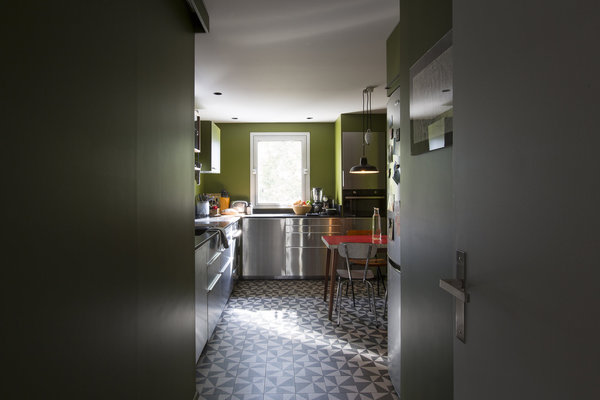 En partie basse, la cuisine de 11 m² est meublée avec des caissons à façades en acier inoxydable (Ikea). En partie haute, des étagères en noyer, issues du système String, rajoutent une touche vintage.