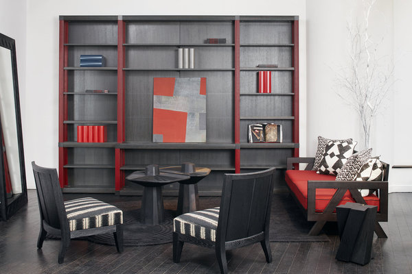 Bibliothèque Library en chêne, encadrée d’un canapé et d’une paire de fauteuils Wallis de la ligne Outdoor. Tables basses Webwood en bois brûlé dessinées par Fabrice Ausset. Au premier plan, le tabouret Zigi en chêne massif sablé.​
