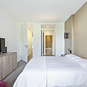 La chambre, mise en valeur par les rangements en noyer américain, s’ouvre sur la salle de bains, comme une suite d’hôtel.