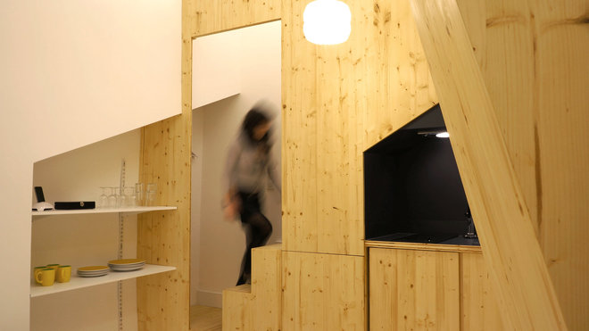 Dans l’entrée, un escalier permet de monter à la mezzanine où se trouve un lit pour deux personnes. Et au contraire, on descend de quelques marches pour accéder à la pièce à vivre. Des étagères intégrées font office de buffet et vaisselier.