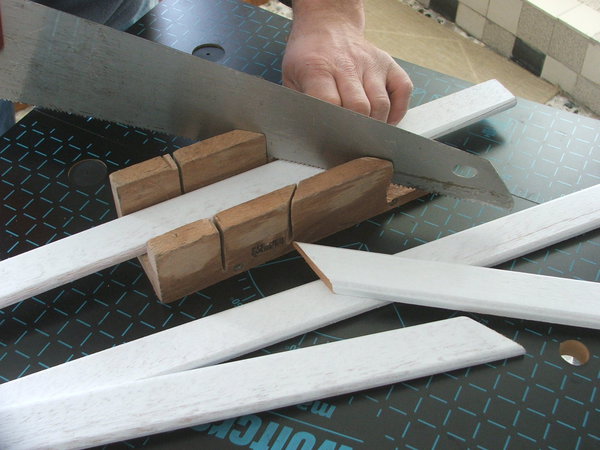 Etape 7 : découpe à la longueur des pare-closes en coupes d’onglet (45°), à l’aide d’une scie à fines dentelures et d’une boîte de coupe d’onglet.