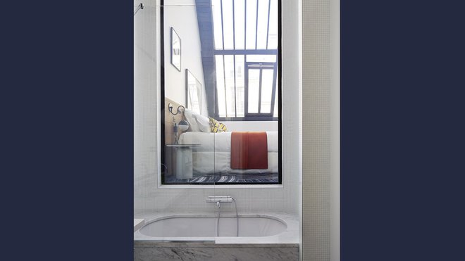 Une vitre éclaire la salle de bains en second jour et en contre-bas de la chambre; le marbre de Carrare répond aux codes du luxe, travaillé dans une forme épurée, sans être ostentatoire.