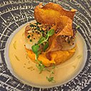 Deux belles noix de coquille Saint-Jacques gratinées aux herbes et aux noix.