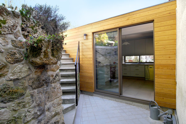 La cour arrière est devenue un nouvel espace de détente. La façade de l’extension nord s’inscrit contre l’escalier existant dont la ferronnerie a été nettoyée et repeinte.