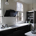 La cuisine séparée est meublée de façon contemporaine, avec un style design épuré et un choix de deux teintes en opposition, le noir et blanc, déclinées dans différentes matières.