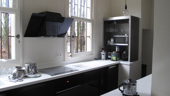 La cuisine séparée est meublée de façon contemporaine, avec un style design épuré et un choix de deux teintes en opposition, le noir et blanc, déclinées dans différentes matières.