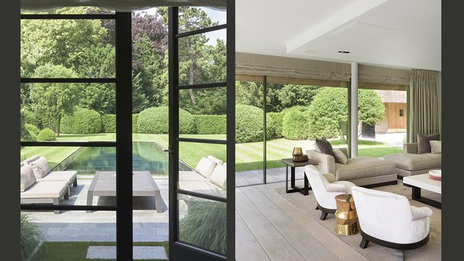 A l'arrière de la maison, le coin salon est plongé dans la lumière naturelle : de grandes baies vitrées coulissantes s’ouvrent en invitant le jardin à entrer dans la pièce à vivre. Les châssis élancés et les hautes fenêtres attirent le regard, et le jardin s’y déploie, tel un tableau grandeur nature. Le coin salon est meublé avec la collection Piet Boon.
