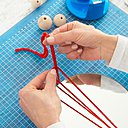 Étape 1 : Découpez un long fil dans votre pelote de laine, puis repliez-le en deux. Enroulez-le ensuite autour de votre miroir et attachez-le à l’aide d’un nœud coulant.