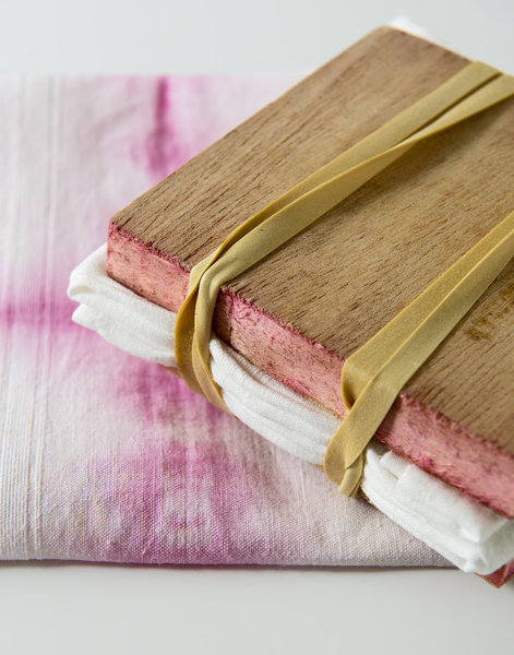 une serviette pliée et maintenue avec 2 planches de bois et des élastiques.