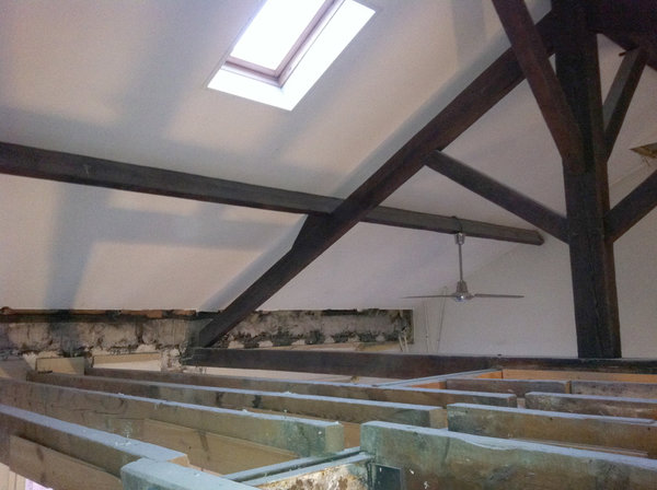 Avant travaux : lors des travaux, la dalle haute a été démolie et abaissée de 40 centimètres pour augmenter la hauteur sous combles trop faible. Des profils métalliques de 7 mètres de long ont été mis en place pour renforcer les façades et assumer la descente de charge. Il a fallu couper la traverse inférieure de la charpente pour ne pas gêner le bon déroulement des travaux.