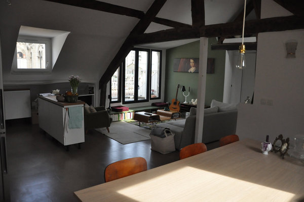La pièce à vivre est baignée de lumière grâce à une double exposition et de vraies fenêtres. La fenêtre donnant sur la terrasse se compose désormais de deux châssis ouvrants au centre encadrés d’un châssis fixe de chaque côté. Un banc intégrant des rangements pour les livres longe le bas de cette ouverture.