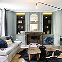 Au rez-de-chaussée, le salon prend place dans un écrin de boiseries d’origine peintes. Le mobilier chiné se mélange sans complexe aux pièces de créateurs. Sur la cheminée, lampe Le Deun. Suspension Potence de Jean Prouvé, chez Vitra.