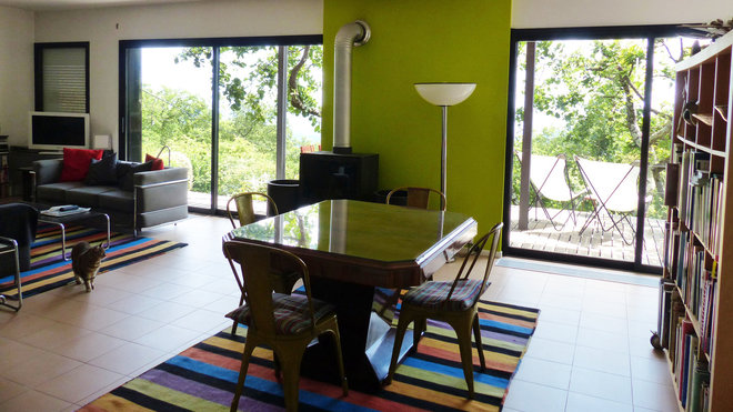 La grande pièce à vivre est personnalisée par un pan de mur peint en vert anis qui sert de support à la cheminée. Chaises industrielles vintage, modèle A, création Xavier Pauchard, éditées chez Tolix. La salle à manger est séparée de la cuisine ouverte par une bibliothèque sans fond et sur roulettes.