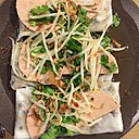 Les rondelles de  mortadelle vietnamienne sont disposées sur les Banh Cuôn, décorez de coriandre et de germes de haricots mungo.