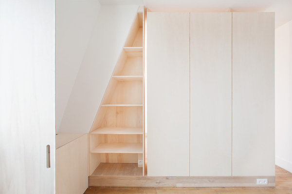 Côté pile, dans la chambre, la tête de lit fait office de séparation de pièce et le mur en soupente a été exploité en bibliothèque. Dans la tête de lit, des rainures, toute hauteur, ont été dessinées pour lui donner l’aspect d’une armoire, en trompe-l’œil.