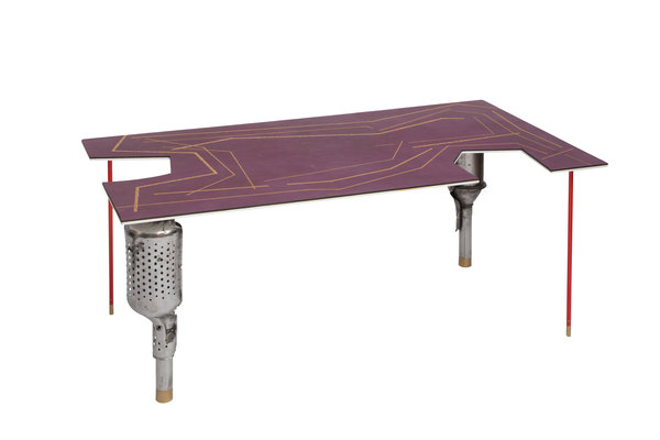Déclinée dans une couleur lilas (tannage naturel), table basse Precious Catalyst avec pieds formés par des catalyseurs de voiture. Plateau recouvert de cuir pleine fleur avec un travail de dorure sur cuir. Le décor de galons classiques de bureau anglais a été réalisé par le gainier d’ameublement bruxellois Francis Dekelver, fournisseur agréé de la Cour de Belgique. Création Lionel Jadot.