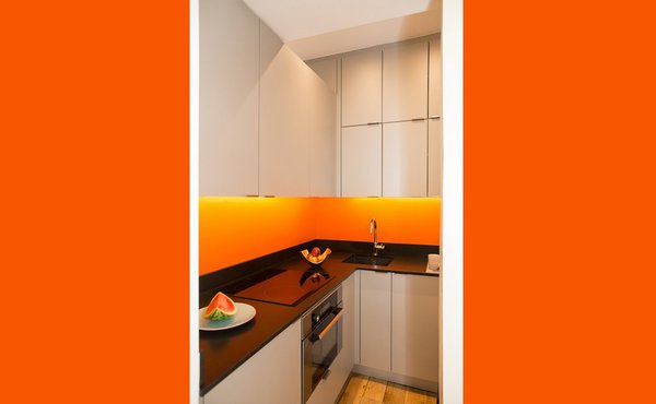 Les rangements de cuisine réalisés sur mesure sont dotés de poignées de portes discrètes, identiques aux rangements filants du couloir et zone de dégagement.