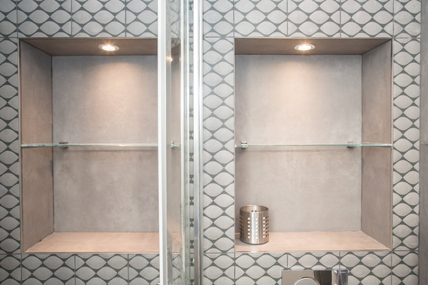 Dans la salle de bains, des niches de rangement avec éclairage intégré optimisent l’espace restreint.
