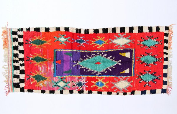 « Découvert en avril 2012, Tazoulait est un village relativement riche, car étant proche d’Alnif et de Rissani. La plupart de ses hommes sont partis travailler à Casablanca ou en France. Les tapis de ce village sont moins spontanés et la structure du dessin reproduit des modèles urbains, comme celui-ci réalisé par Fatima Oumalouk ».