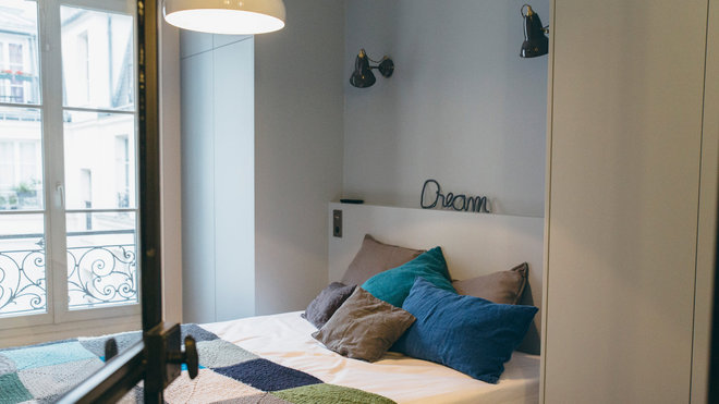 Un lit encadré de deux dressings sur mesure avec une tête de lit dotée d’une tablette de 10 cm de profondeur. Suspension Spinning Light BH2, création Benjamin Hubert, éditée par & Tradition. Appliques, modèle Original 1227, édité par Anglepoise, chez Fleux’.