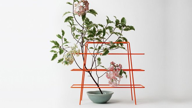 Designerbox n° 11 : Babylone est un accessoire de table ou de bureau polyvalent pour poser une plante grimpante, des dossiers, une tasse…. En fil d’acier laqué orange (L 26 x P 9,5 x H 20 cm).  Création Harri Koshinen.