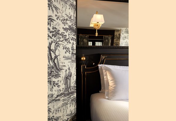 Le noir, une des couleurs phare du style Directoire, réinterprétée dans une chambre au papier évoquant une ancienne Toile de Jouy.