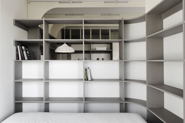 Côté pile, le mur courbe qui structure l’espace supporte les étagères d’une bibliothèque et dessine une cloison pour la chambre.