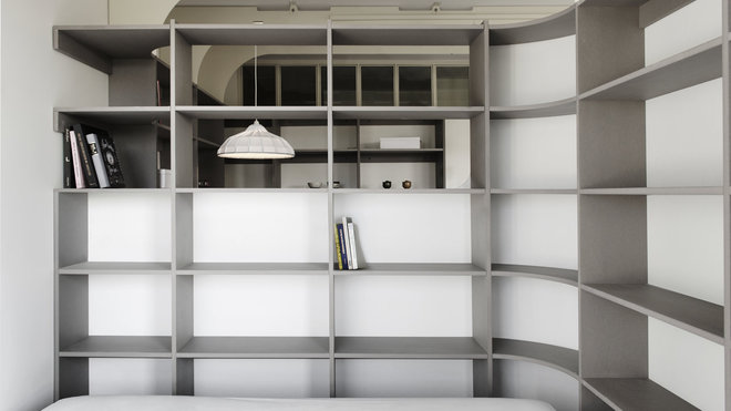 Côté pile, le mur courbe qui structure l’espace supporte les étagères d’une bibliothèque et dessine une cloison pour la chambre.