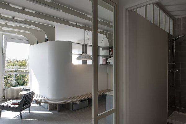 L’espace d’accueil, qui regroupe un espace rangement et la salle de bains, compose un espace intermédiaire avec une large baie vitrée typique des ateliers parisiens qui permet de cloisonner tout en apportant de la lumière naturelle.