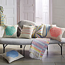 Harmonie pastel avec un mélange de coussins aux couleurs douces dont certains sont tricotés au point de jersey sur un canapé aux formes organiques. Chez Madura.